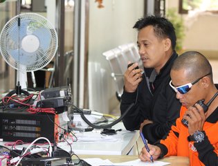 Two Filipino emergency responders use technological equipment to coordinate the local authority's response to a typhoon disaster.