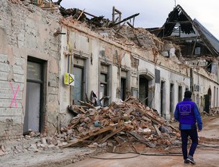 An EU humanitarian worker walks through an empty earthquake-hit street in Croatia.