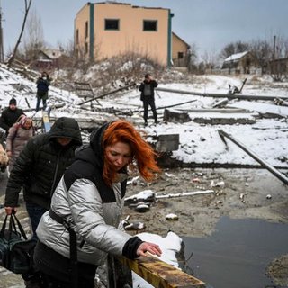 Civilians cross a river on a blown up bridge on Kyiv's northern front on March 1, 2022