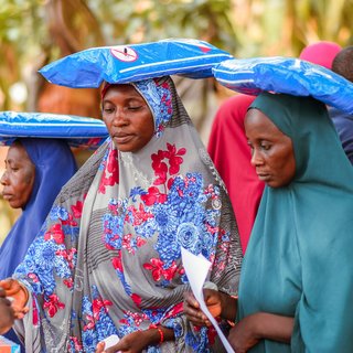 Nigeria women in Abuja carrying sacks on their heads while learning about health and hygiene during the COVID-19 pandemic